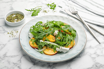Tasty salad with arugula, cheese, peach, basil and spices on white marble table, closeup