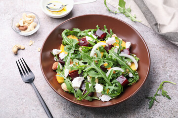Tasty salad with arugula, cheese, peach, beetroot and nuts on grey table, above view