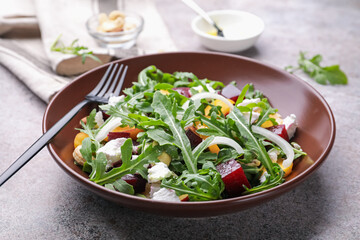 Tasty salad with arugula, cheese, peach, beetroot and nuts on grey table, closeup