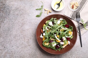 Tasty salad with arugula, cheese, peach, beetroot and nuts on grey table, flat lay. Space for text