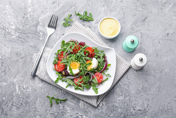 Tasty salad with arugula, vegetables and egg served on grey table, flat lay