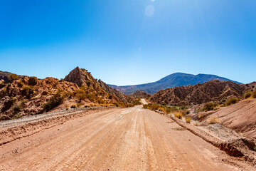 Vast and rugged desert landscape with a dusty road leading into the distant mountains of the Argentine Andes.