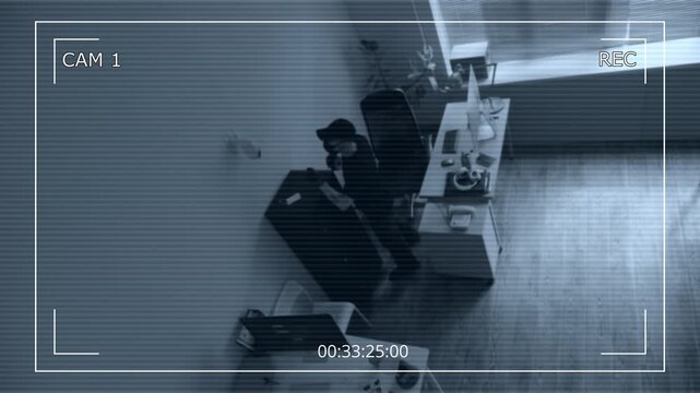 CCTV footage of masked male criminal blocking surveillance camera on wall with adhesive tape blinding security system then hacking into computer while spying in corporate office