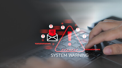 System warning alert showing cybersecurity threat with phishing email icon. The user is typing on a laptop during a malware attack or a system vulnerability warning.