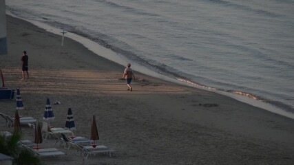 People walking in the coast of Durrës beach in Albania at sunrise. June 16, 2025.