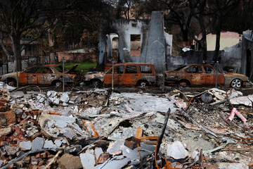 Aftermath of a devastating wildfire three burned cars and destroyed house