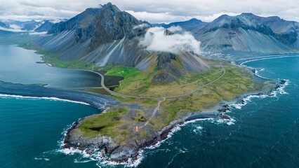 Fototapeta premium A majestic aerial view captures Hvelnes nature reserve mountain rising dramatically above the coastal landscape of Iceland.