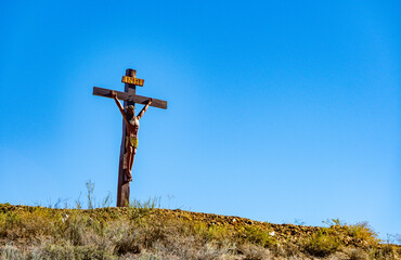 A wooden crucifix stands atop a dry hill in Valle de Luracatao, Salta, starkly outlined against a...