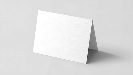 A blank white card standing on a white surface with a subtle shadow in a minimalist style setting