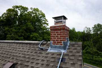 Close-up of Brick Chimney with Flashing and Electrical Conduit on Asphalt Shingle Roof