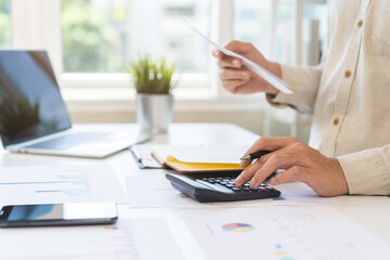 Stressed asian young businessman, employee male using calculator to calculate expenses of monthly,...