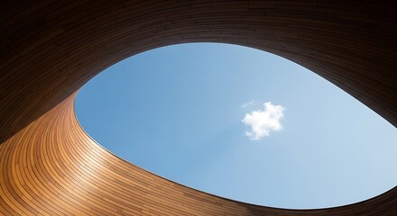 Obraz premium Looking up through a curved wooden structure at a bright blue sky with a single white cloud