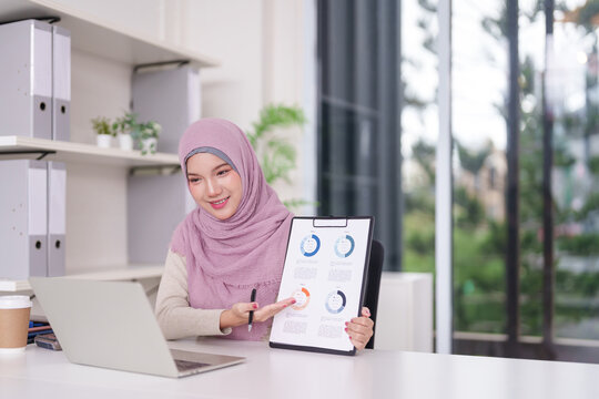 Muslim Businesswoman Presents Data Analysis Via Laptop Video Conference Discussing Strategy In Modern Professional Office Workspace For Remote Work Success