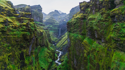 A breathtaking landscape of Mulagljufur Canyon reveals towering green cliffs and a flowing river in Iceland