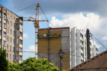 Workers diligently painting a high-rise building under a bright sky in an urban construction scene