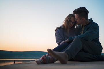 Couple on the pier at lake, summer sunset