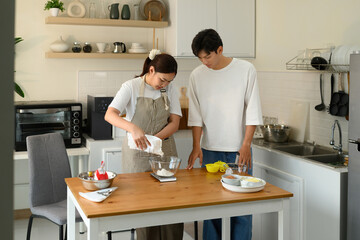 A Young Asian couple preparing baking ingredients together in a cozy modern kitchen