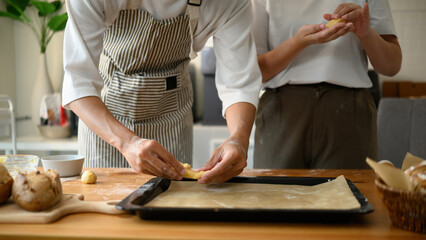 Close-up image of Hands working with fresh cookie dough and placing it on a tray while baking at...
