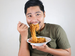 close up of Handsome Asian man enjoying noodles with a fork. Eating lunch concept. Isolated white background