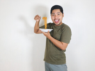 happy Handsome Asian man enjoying fried noodles with a fork. Eating lunch concept. Isolated white background