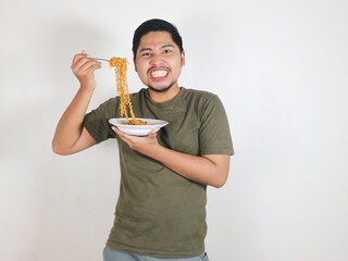 Handsome Asian man holding noodles with a fork while showing anger and exasperation. eating lunch...