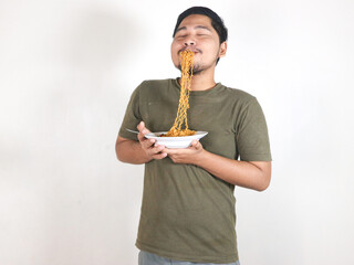 Handsome Asian man enjoying noodles, with the noodles still in his mouth. Eating lunch concept. Isolated white background