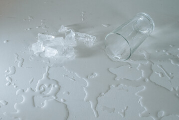 Glass and melting ice on spilled water, contrast of textures and temperatures.

