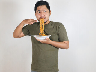 Handsome Asian man holding noodles with a fork while showing a spicy expression. eating lunch concept. isolated white background