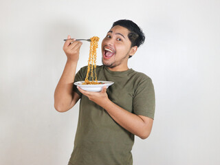 happy Handsome Asian man enjoying fried noodles with a fork. Eating lunch concept. Isolated white...