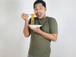happy Handsome Asian man enjoying fried noodles with a fork. Eating lunch concept. Isolated white background