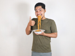 Handsome Asian man enjoying noodles, with the noodles still in his mouth, and giving a thumbs up. eating lunch concept. isolated white background
