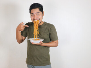 Handsome Asian man enjoying noodles, with the noodles still in his mouth. Eating lunch concept....