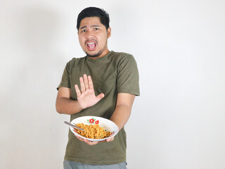 Handsome Asian man holding noodles and showing a refusal pose by pushing the noodles away. eating lunch concept. isolated white background