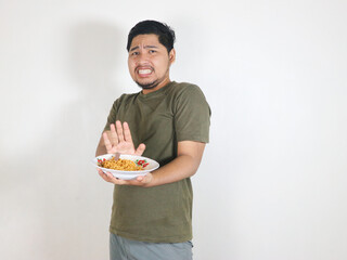 Handsome Asian man holding noodles and showing a refusal pose by pushing the noodles away. eating lunch concept. isolated white background