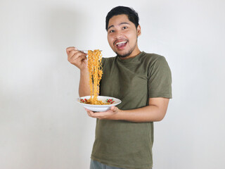 happy Handsome Asian man enjoying fried noodles with a fork. Eating lunch concept. Isolated white...