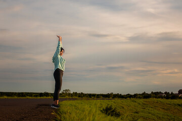 A plump young woman warms up before exercising for better health during sunset.