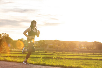 A plump young woman is exercising by jogging for better health during sunset.