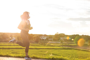A plump young woman is exercising by jogging for better health during sunset.