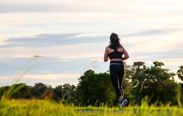 A plump young woman is exercising by jogging for better health during sunset.