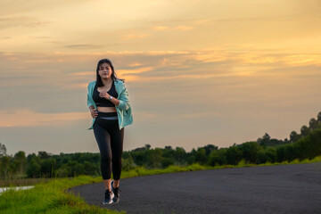 A plump young woman is exercising by jogging for better health during sunset.