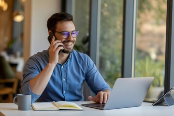 Man talking on phone working on laptop desk