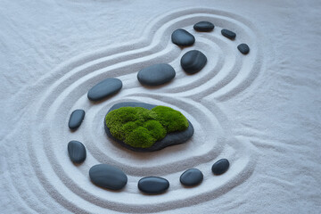 Smooth gray stones and vibrant green moss arranged on raked white sand zen garden raked sand