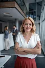 Fototapeta premium Portrait of successful businesswoman smiling with crossed arms in modern office
