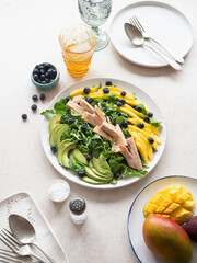 Tuna fish salad with mango, avocado and blueberries on white table