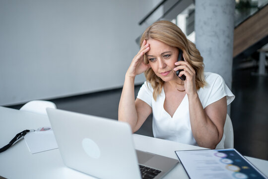Businesswoman stressed while talking on phone and working on laptop - Powered by Adobe