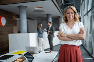 Confident businesswoman smiling with crossed arms in modern office