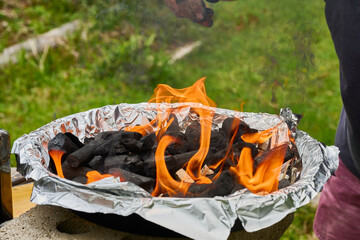 Burning charcoal in a portable barbecue covered with aluminum foil