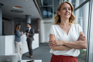 Confident businesswoman smiling with folded arms in modern office