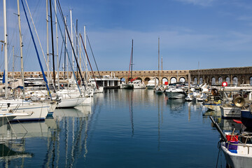 Marina with sailboats and yachts in Antibes on the Cote d'Azur with city walls and snow-capped mountains in the background, in spring