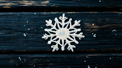 Fototapeta premium A delicate snowflake on a dark wooden plank standing out with its intricate design 